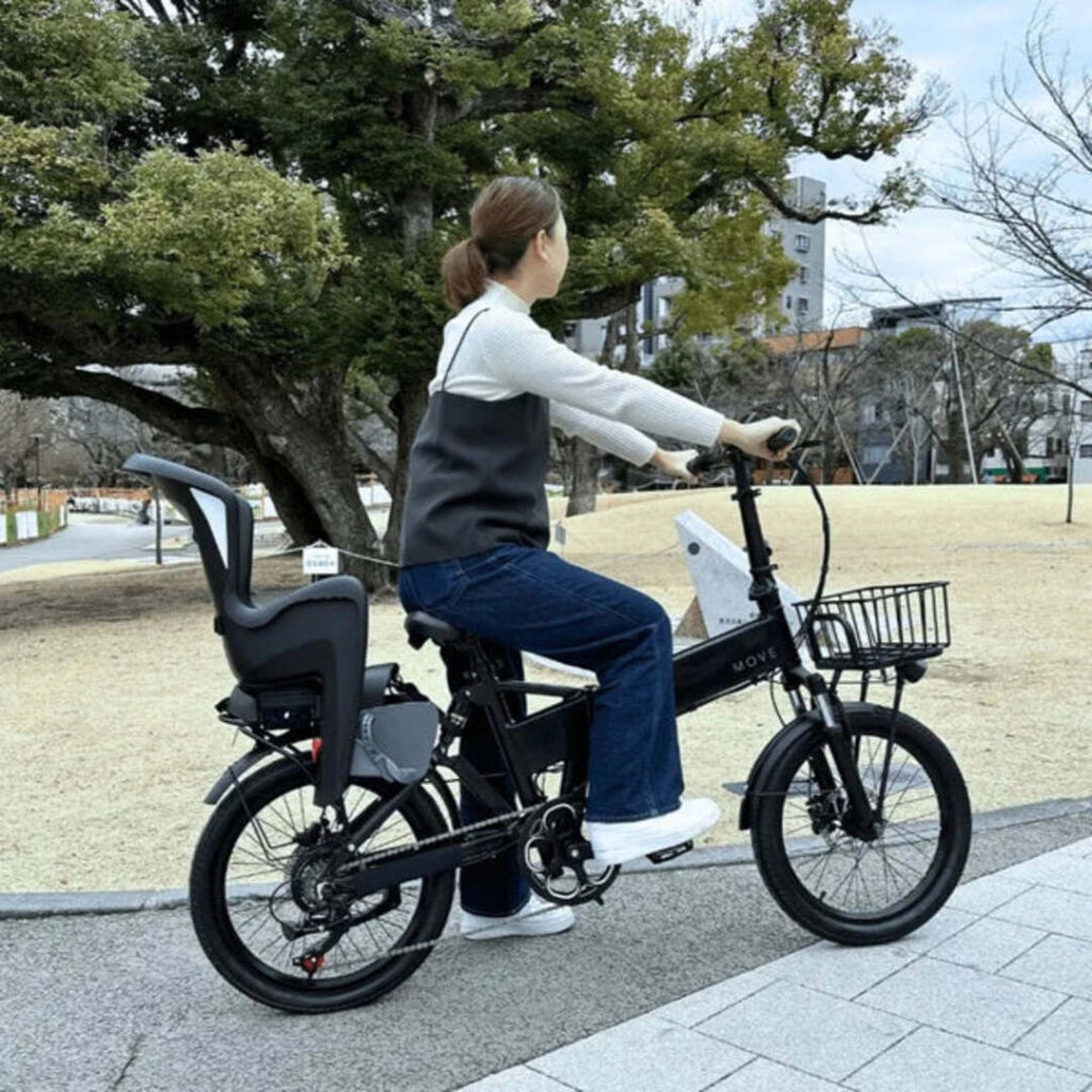 チャイルドシートとかごがついた電動自転車にママさんがまたがっている