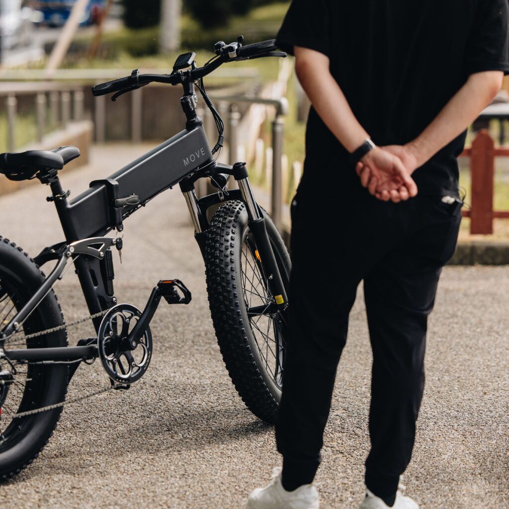 電動自転車MOVEを川沿いで後ろに手を組んでみている男性