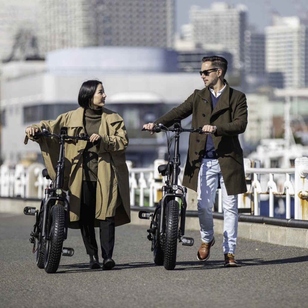 電動自転車MOVE愛用者の外人さんと女性がハーバー前で電動自転車を押しながら話をしている様子