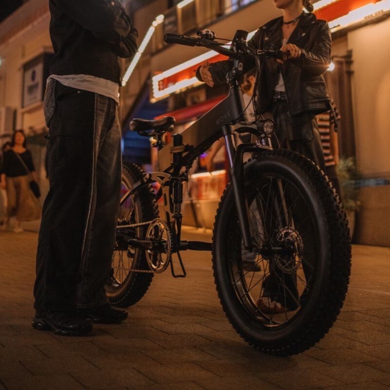 夕方暗闇の中で電動自転車を挟んで話に花が咲く2人の男女