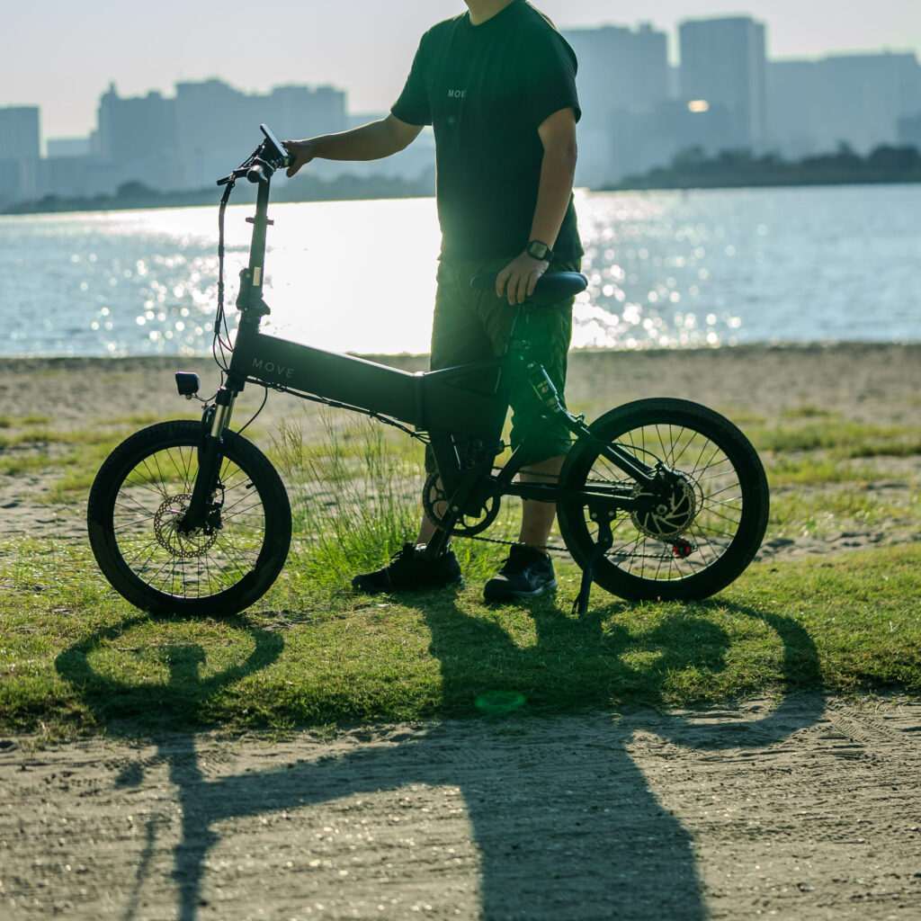 電動自転車を押しながら川の前できらめている