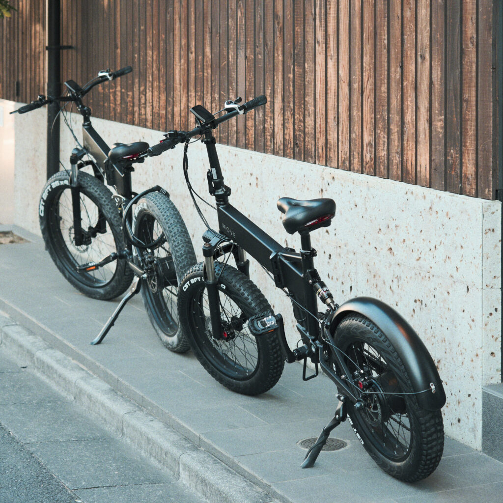 2つの電動自転車が木造建築の建物に寄りかかっている様子