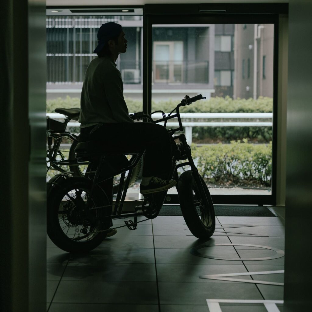 暗闇で電動アシスト自転車と佇む男性