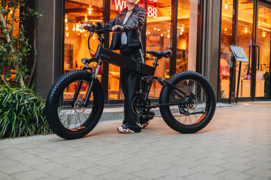 電動自転車MOVEを愛用している女性がおしゃれな道を歩いている様子